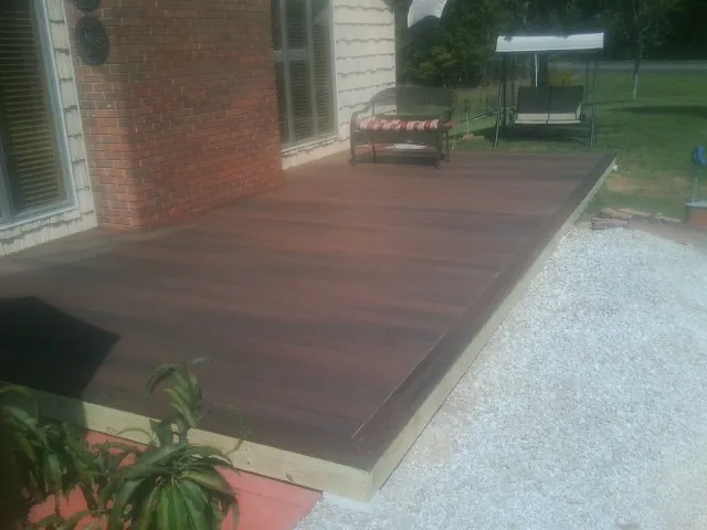 Freshly stained wood deck built against a brick home in West Point